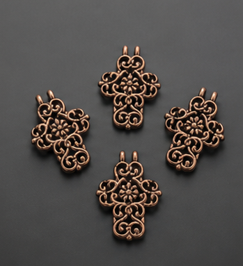 A set of four antiqued copper openwork filigree cross charms with dual loop connectors arranged neatly on a dark matte surface.