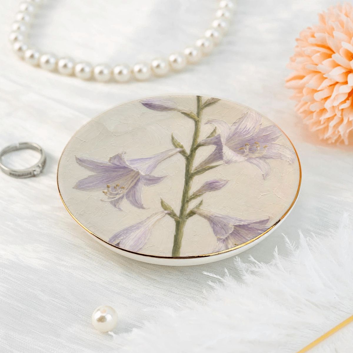 Overhead view of a single round ceramic trinket dish showcasing a lavender floral motif placed near a white pearl necklace.