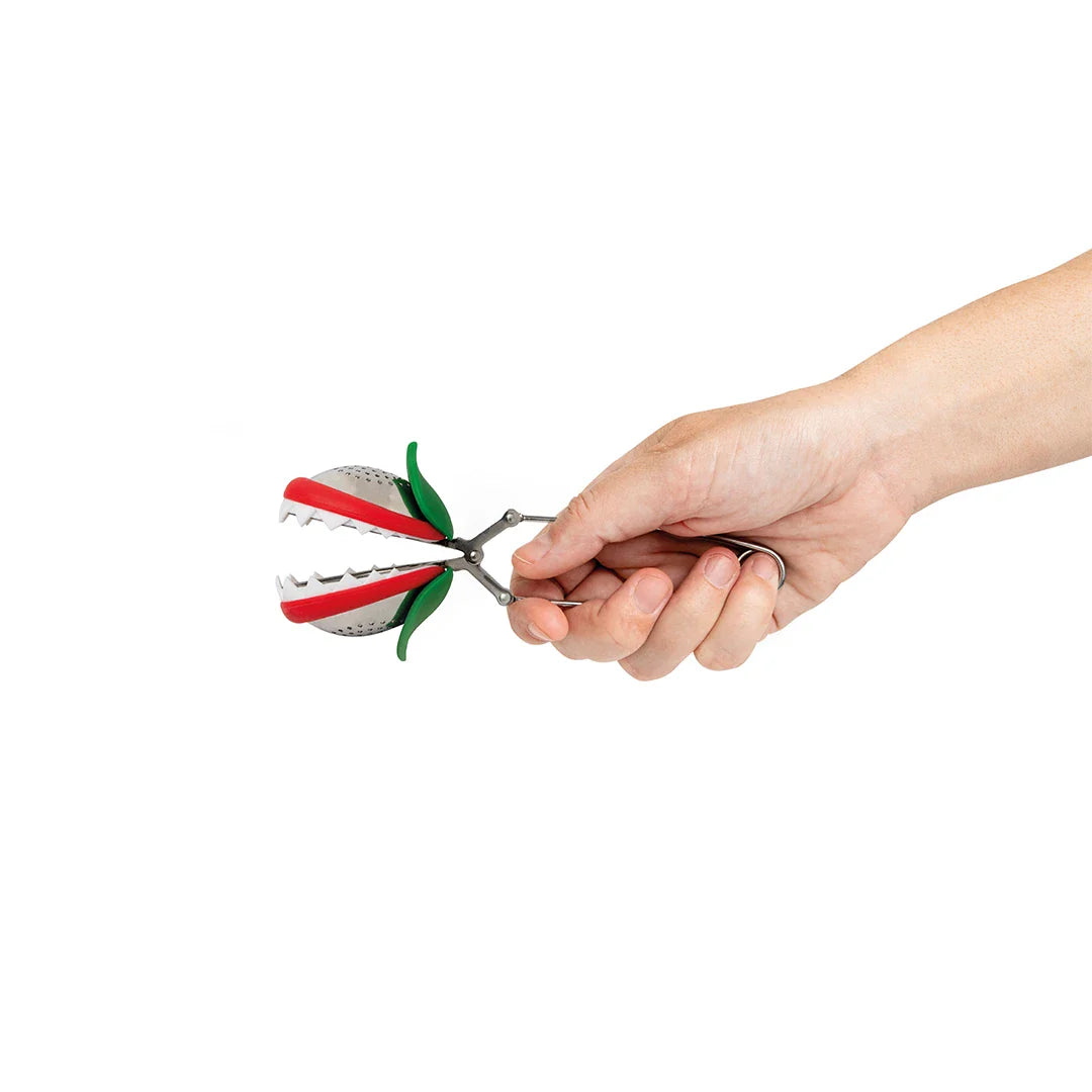 A hand squeezing the stainless steel spring handle to show the mesh tulip tea pod opening up.