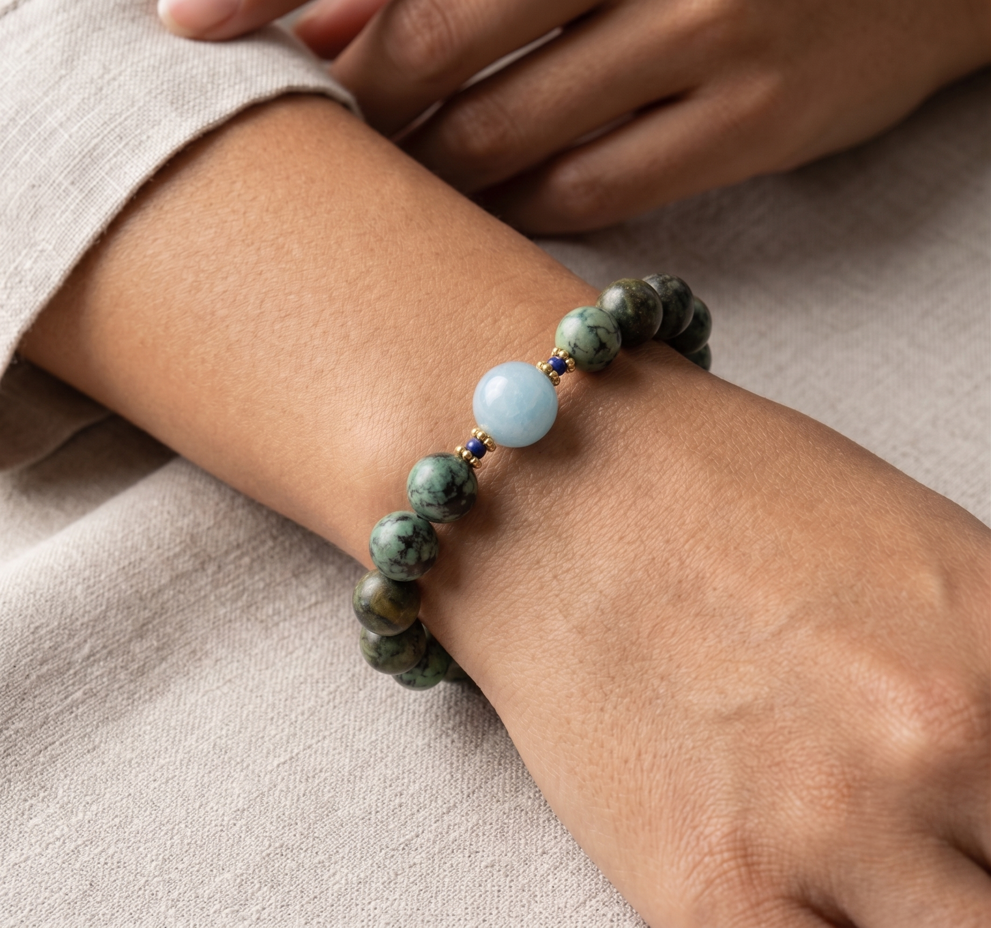 A lifestyle view showing the African turquoise and blue quartz stretch bracelet being worn on a person's wrist against a soft linen sleeve.