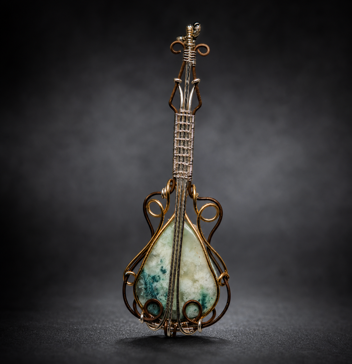 detailed handcrafted wire-wrapped guitar pendant featuring a teardrop-shaped turquoise and white chrysocolla in quartz stone body, resting vertically 