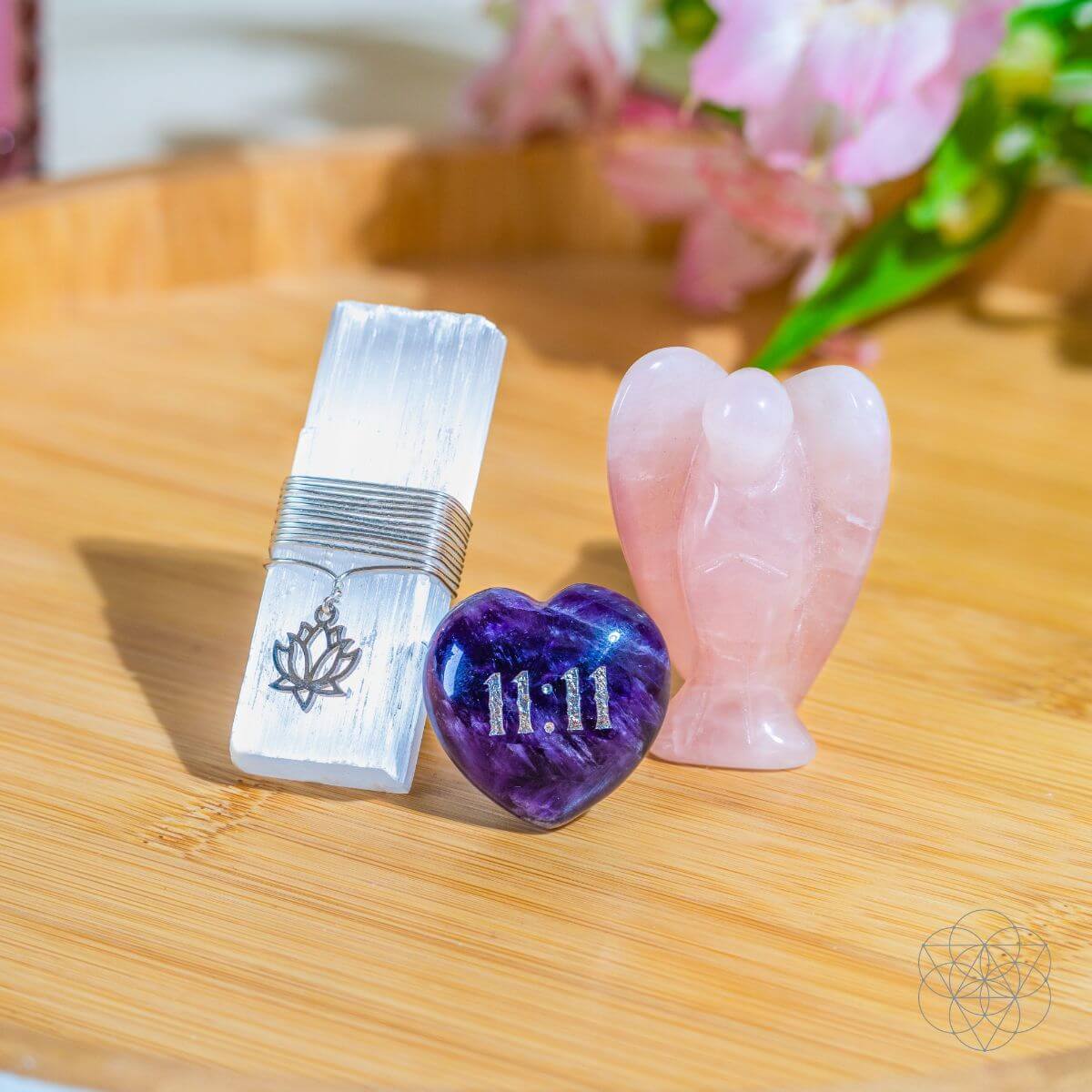The protective car crystal set resting beautifully on a curved wooden tray bathed in natural sunlight with pink floral accents in the background